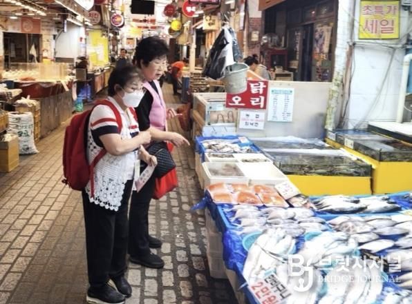지역 어르신이 창4동 지역사회보장협의체 위원과 생선을 사고 있다.