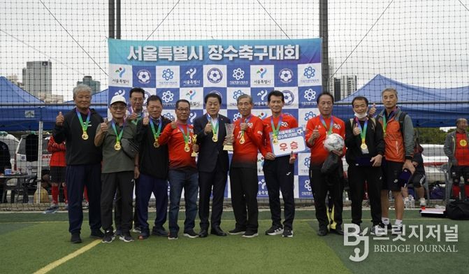 지난 10월 11일과 12일, 성동구 살곶이체육공원 축구장에서 열린 ‘서울시 7080 장수축구대회’에 참석한 김용호 서울시의원(왼쪽 여섯 번째)이 70대B조에서 우승한 용산구 70대 장수축구단에게 우승컵과 트로피를 시상한 후 기념촬영을 하고 있다.