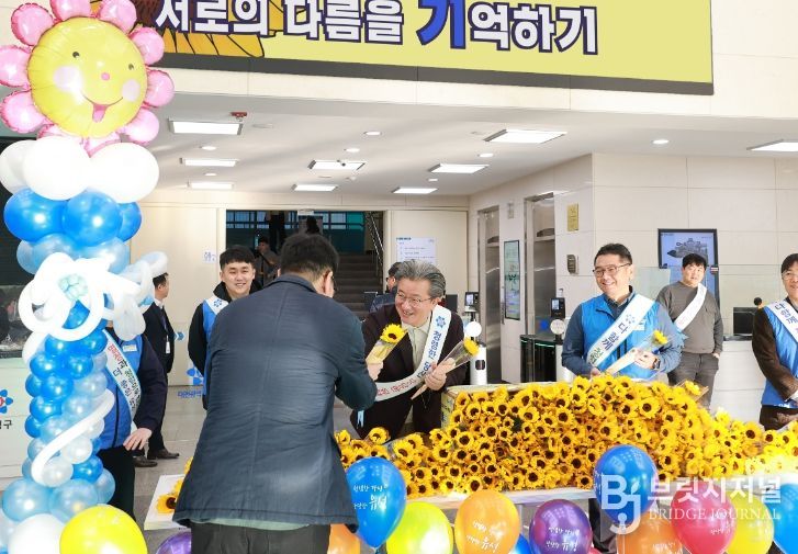 14일 유성구청 본관 로비에서 정용래 유성구청장이 출근하는 직원에게 해바라기꽃을 전달하고 있다