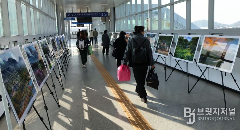 영천역 승강장 입출구 통로에 전시된 제17회 영천관광 전국사진공모전 입상작품을 철도 이용객들이 관람하고 있다.